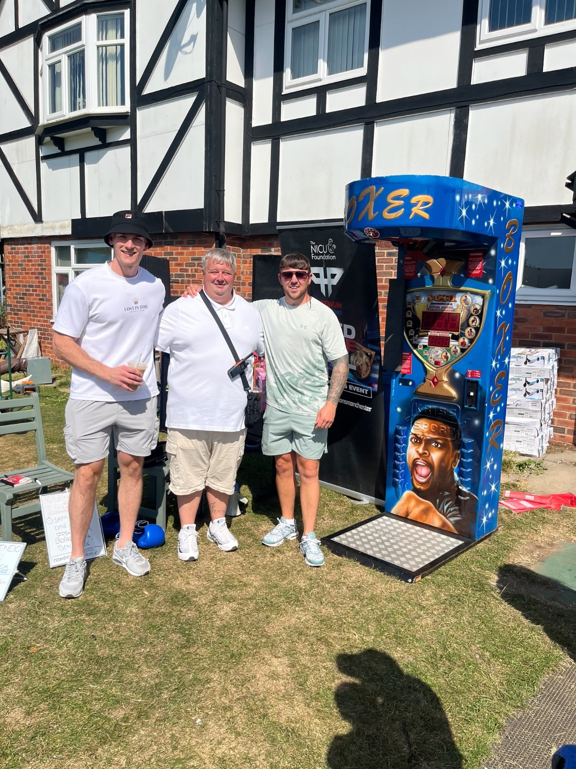Platinum Promotions team posing with the charity boxing arcade machine at the community event